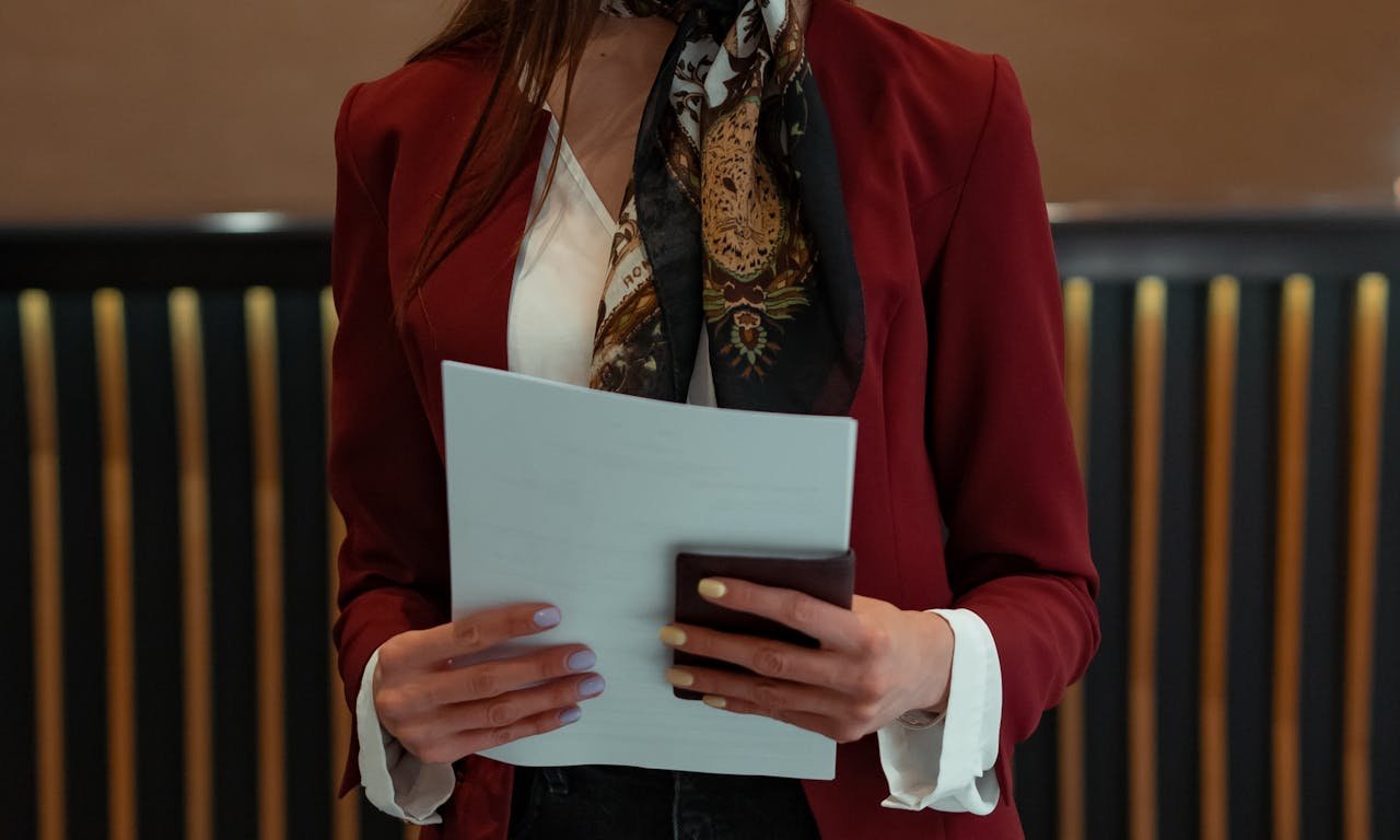 Mastering the First Impression: Your intriguing post title goes here Hotel receptionist holding documents and wallet in formal attire, ready to assist guests.